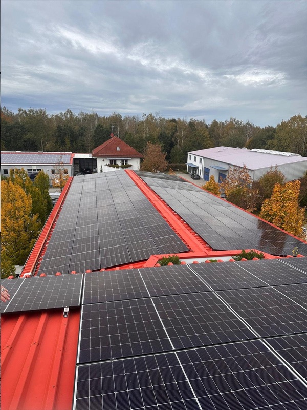 Große Photovoltaik-Aufdachanlage auf einem Gewerbegebäude mit rotem Trapezblechdach